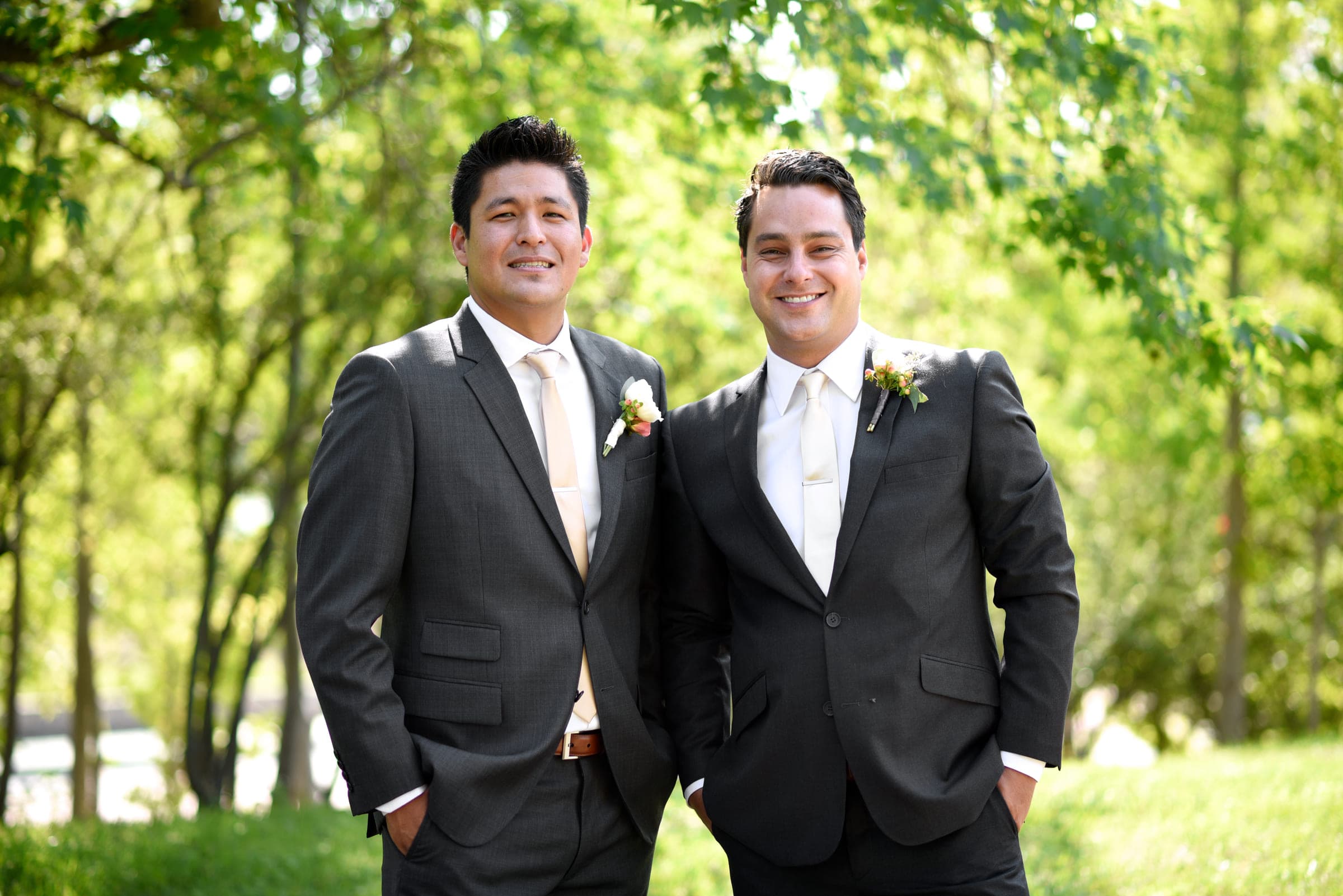 Justin in a suit with a friend at an outdoor wedding