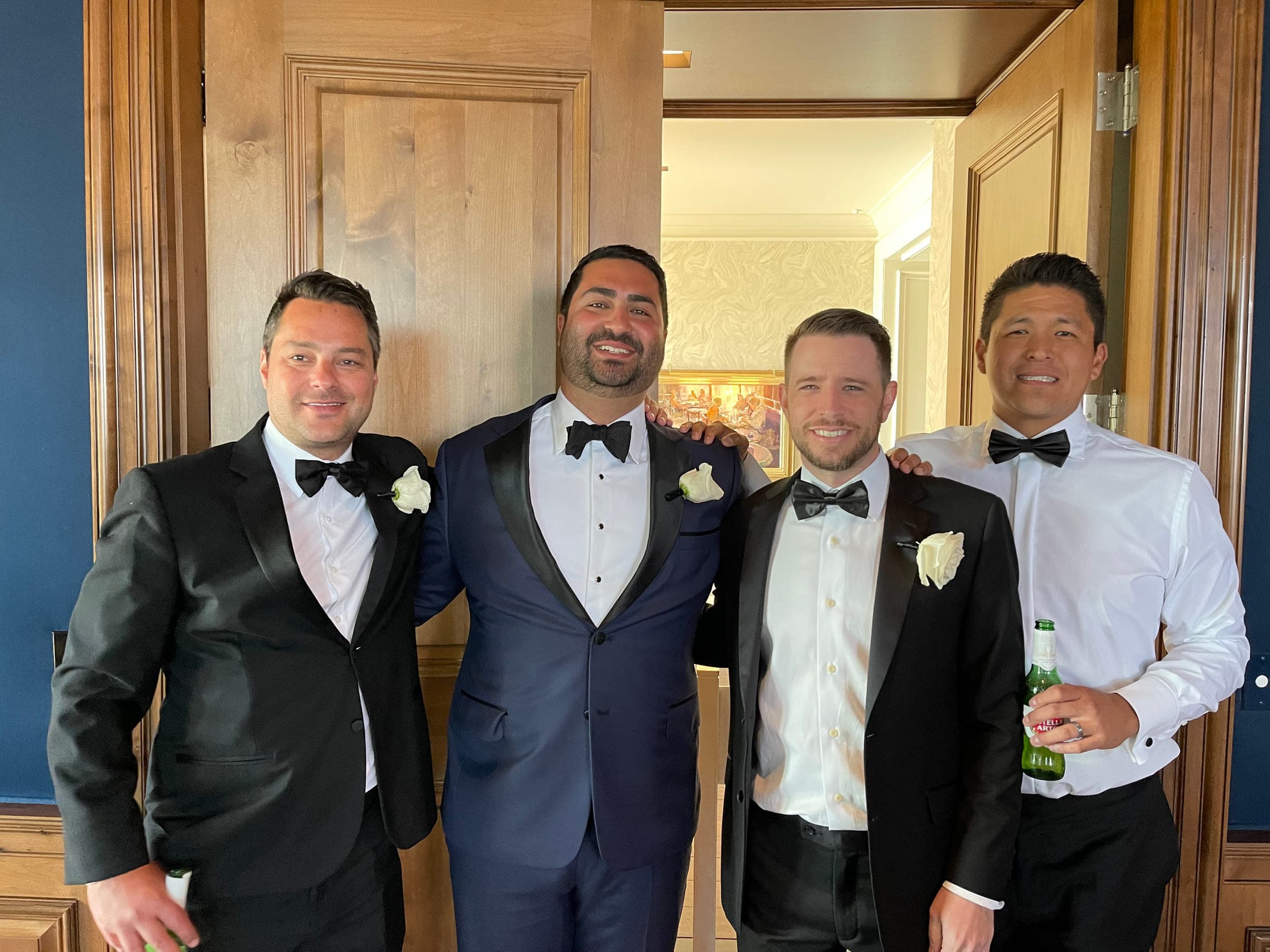 Justin in a tuxedo with three friends at a wedding