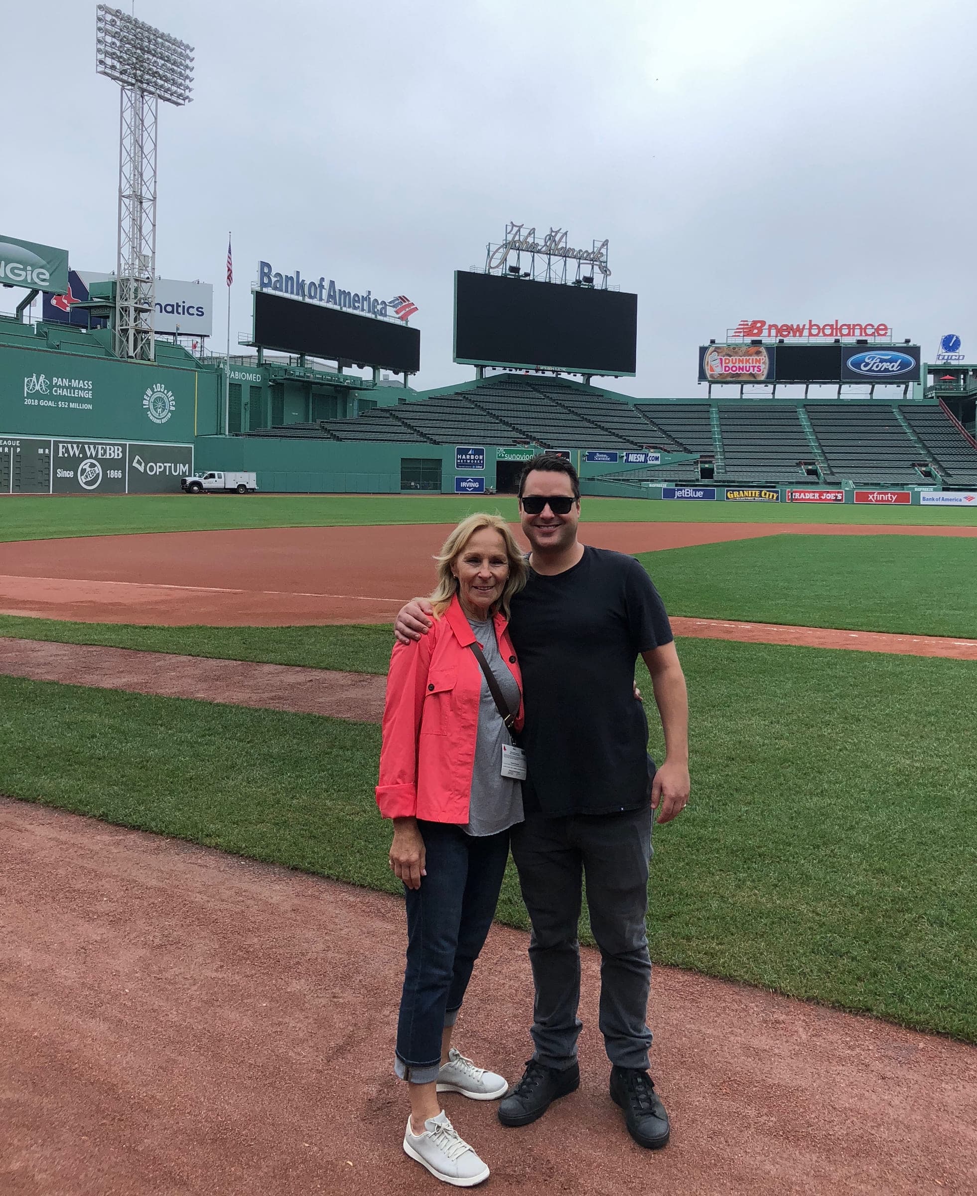 Justin on the field at Fenway Park with his arm around a woman in a red jacket