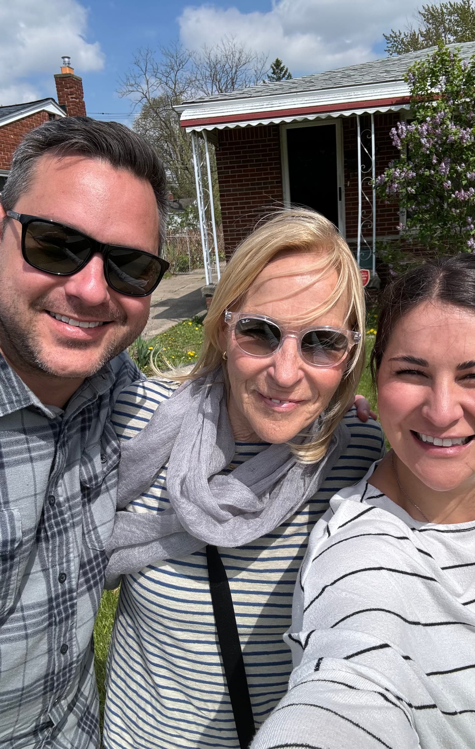 Justin smiling outdoors with two women on a spring day